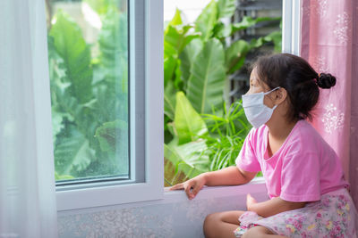 Woman looking through window at home