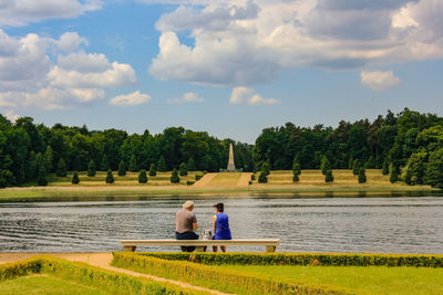 People sitting by trees against sky