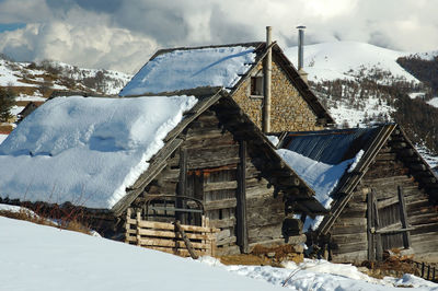 Snow covered houses by buildings against sky