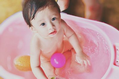 Portrait of cute baby boy sitting in bathtub at home