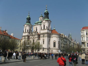 People walking on street by st nicholas church against clear blue sky