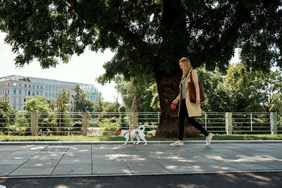 Woman with dog by plants against trees