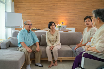 Friends using digital tablet while sitting on sofa at home