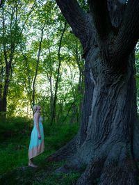 Woman standing by tree in forest