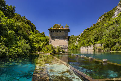 Built structure by lake against blue sky