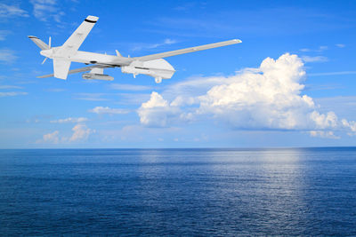 Airplane flying over sea against sky