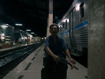 Portrait of man sitting at railroad station platform