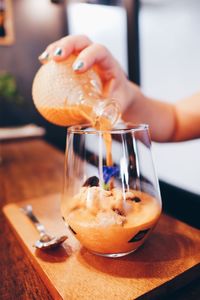 Close-up of hand holding drink on table