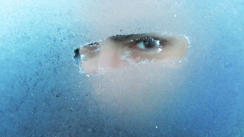 Portrait of woman looking through condensed glass