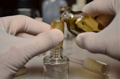 Cropped hands of person pouring perfume into spray bottle