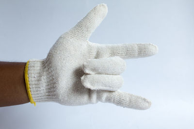 Close-up of hand holding hat against white background