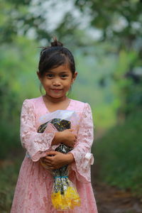 Portrait of young woman standing against trees