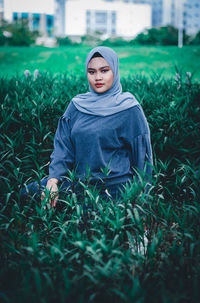 Portrait of young woman sitting amidst plants