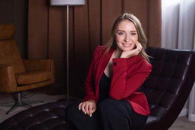 A cute girl in a red jacket is sitting on a couch in the psychologist's office