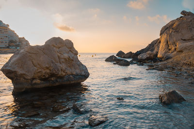 Rock formation on sea against sky during sunset