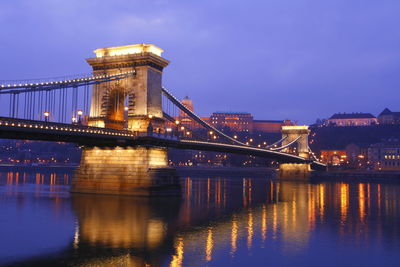 Illuminated bridge over river at night