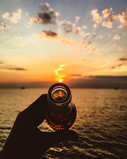 Cropped image of beer against sky during sunset