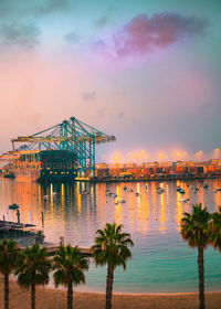 Illuminated pier by sea against sky during sunset