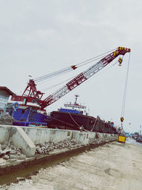 Low angle view of cranes at construction site against sky