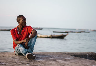 Man sitting in sea against sky