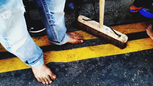 Low section of men with broom while standing outdoors