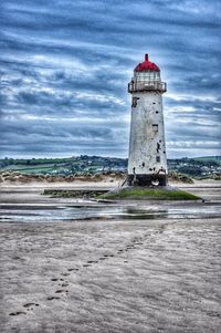 Lighthouse by sea against sky