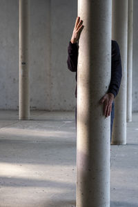 Midsection of woman with umbrella standing on concrete wall