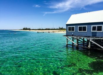 Stilt house in sea against sky