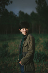 Young man looking away while standing on plants