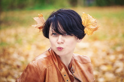 Portrait of smiling woman with autumn leaves on head