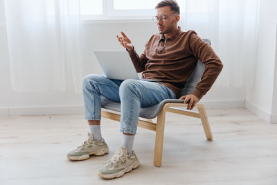 Young woman using mobile phone while sitting on sofa at home