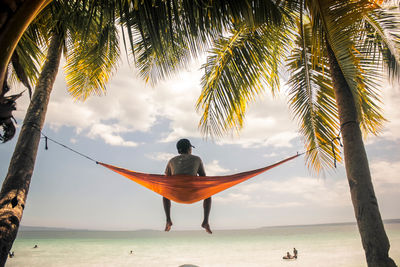 Rear view of man on beach against sky