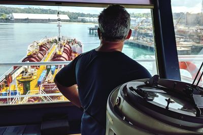 Rear view of man standing by boat in sea