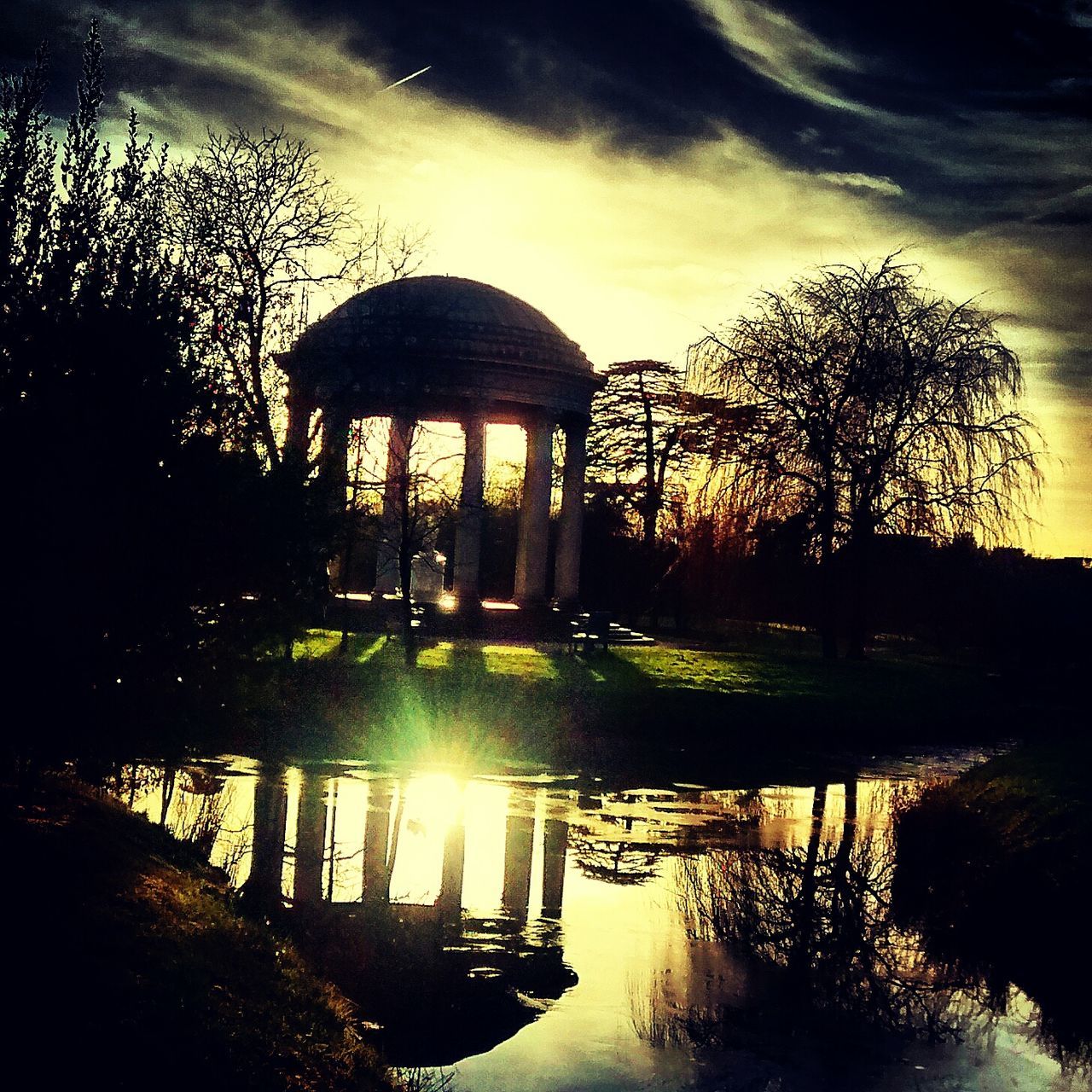 tree, built structure, architecture, sunset, water, silhouette, sun, sky, reflection, sunlight, gazebo, tranquility, park - man made space, sunbeam, nature, arch, river, pond, tranquil scene, building exterior