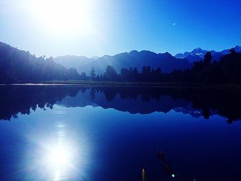 Scenic view of lake and mountains against clear blue sky