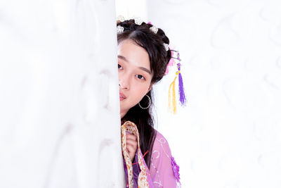 Portrait of young woman standing against wall