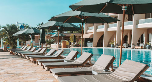 Lounge chairs and parasols by swimming pool