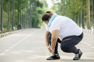 Full length of young man looking away while walking on footpath