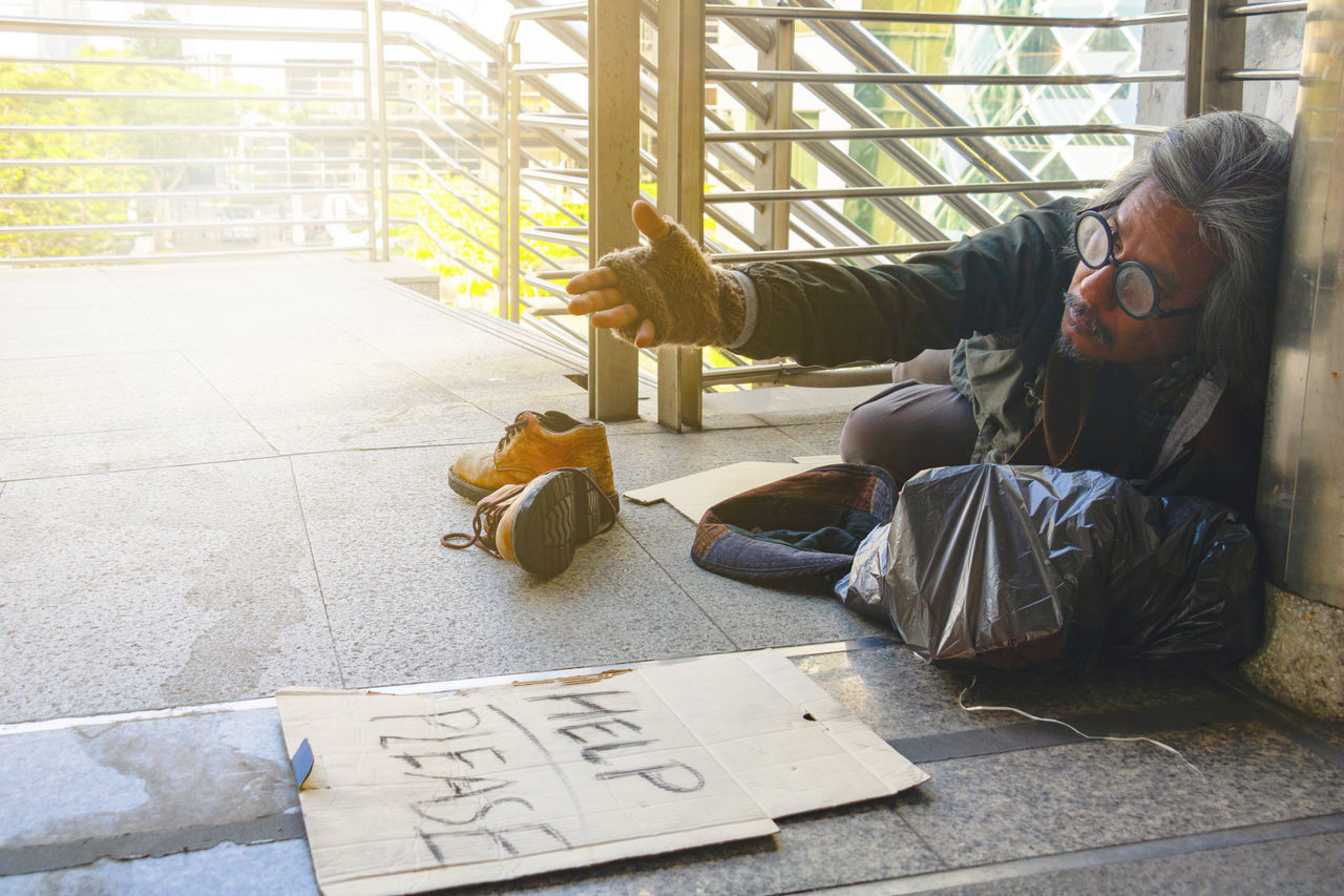 MAN LYING DOWN SITTING ON FLOOR AGAINST WALL