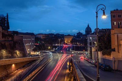 Light trails on road amidst buildings at night