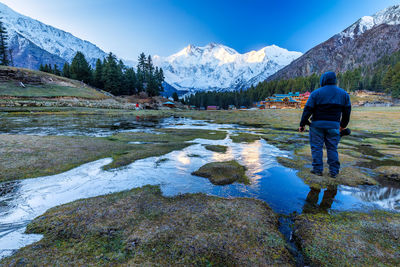 Rear view of man walking on snow covered mountain