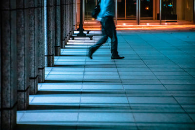 Low section of man walking on illuminated walkway