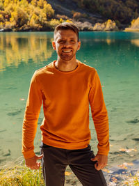 Portrait of young man standing against lake