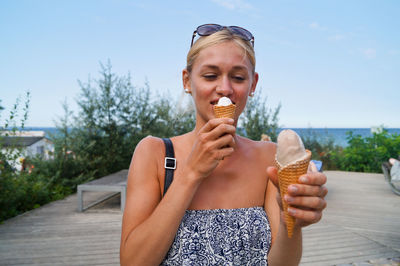 Portrait of woman with ice cream against blue sky