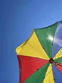 Low angle view of parasol against clear blue sky