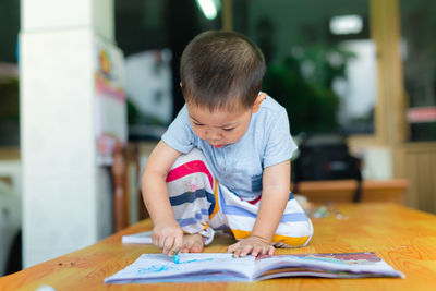 Boy drawing on book at table