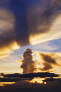 Low angle view of sunlight streaming through clouds during sunset