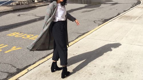 Low section of woman standing on sidewalk by road