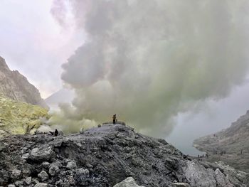 People on mountain against cloudy sky