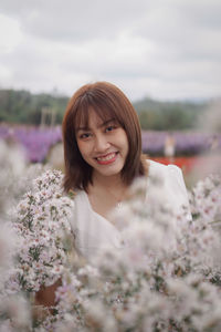 Portrait of young woman standing against sky